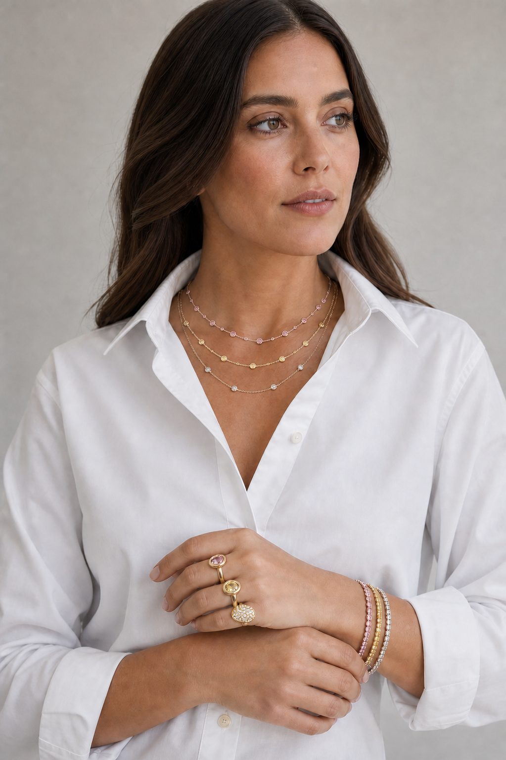 Model wearing pink, yellow, and white diamond station necklaces, tennis bracelets, east-to-west rings, and a yellow diamond dome ring